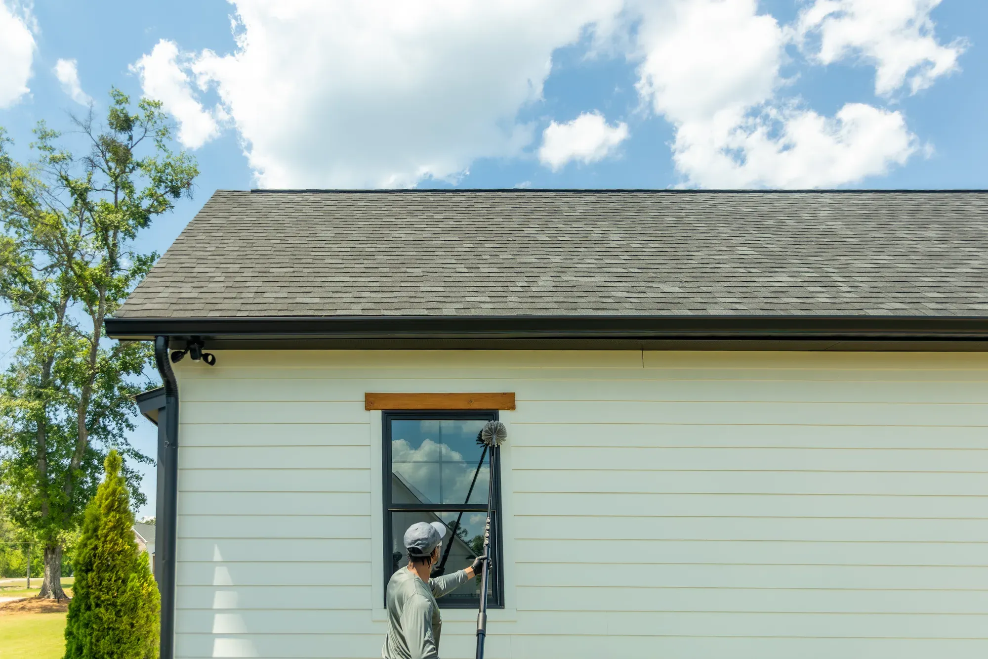 Cape Cod Mosquito Squad technician using a long pole brush to clear webbing