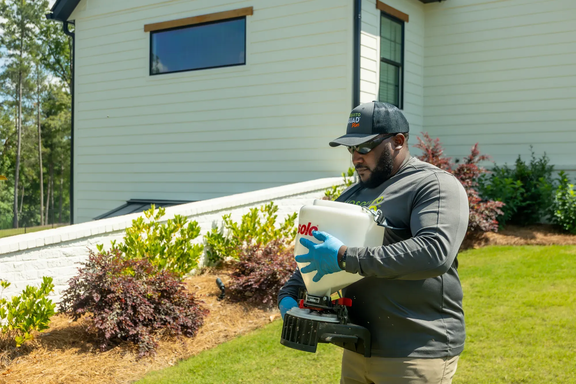 Cape Cod Mosquito Squad technician with a yard treatment spreader