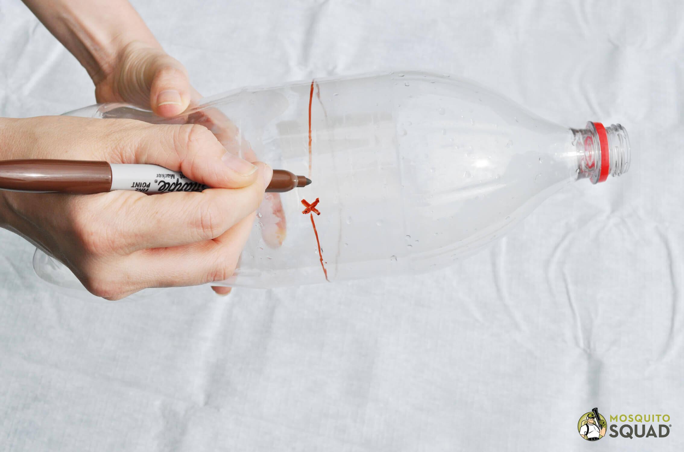 a hand drawing a circle around the circumference of a plastic bottle