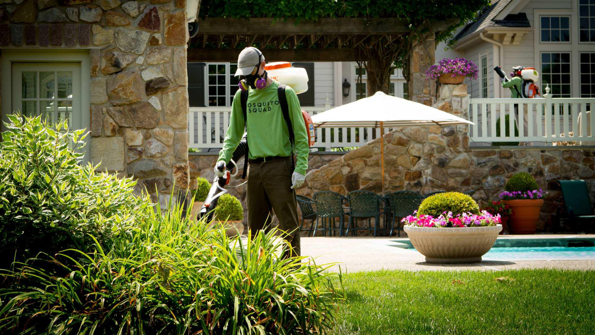 A person wearing a mask and gloves holding a lawn mowerDescription automatically generated