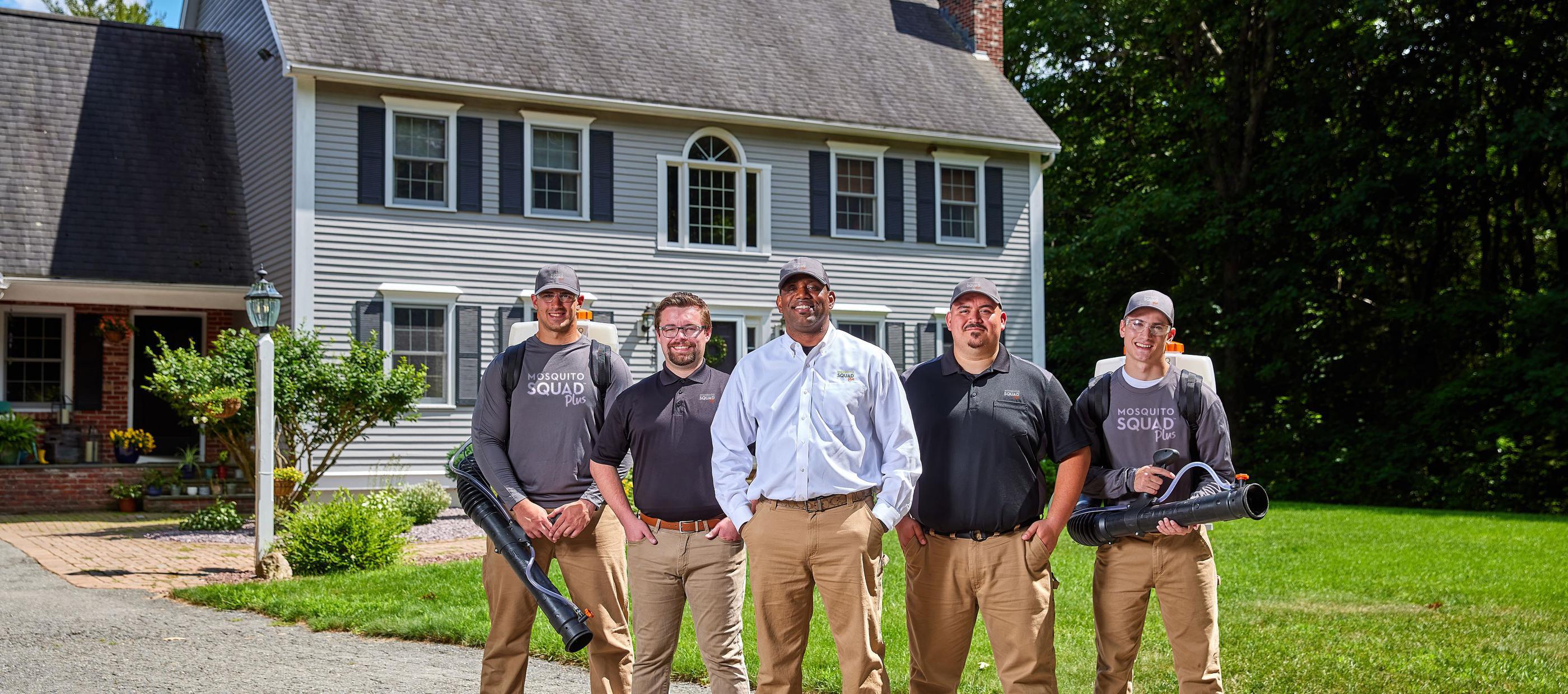Mosquito Squad team standing side by side in front of two story house