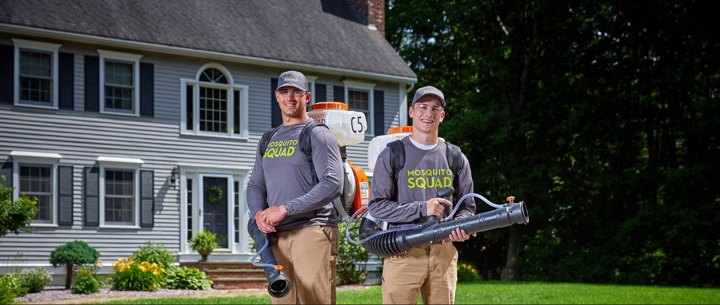 Two men standing in front of house with pest control sprayers