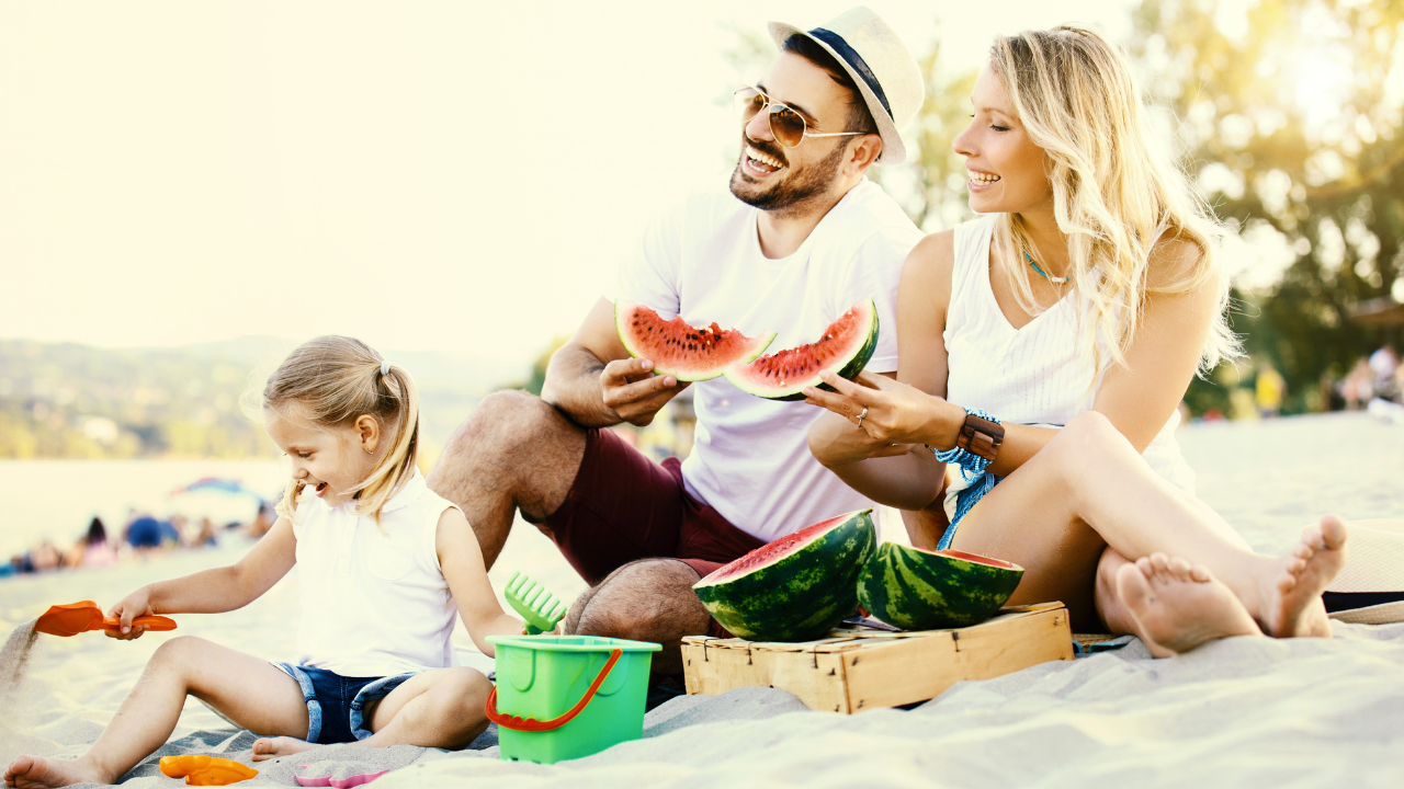 family at the beach eating watermelon